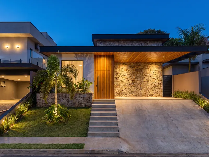Fachada frontal da residência iluminada ao anoitecer, em Atibaia